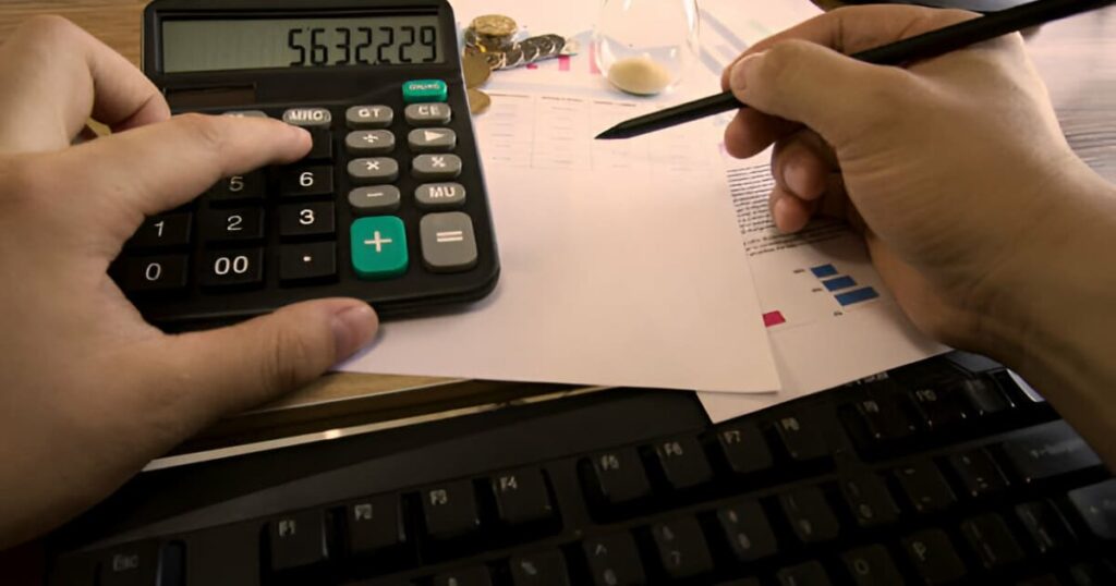 Manos de hombre haciendo cálculos con calculadora y una pluma
