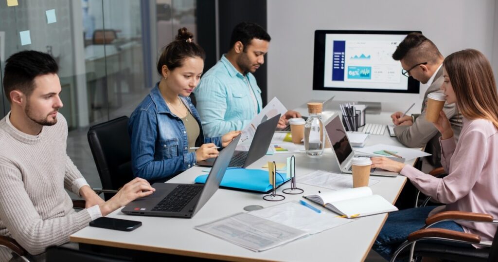 Oficina con personas trabajando en equipos de cómputo