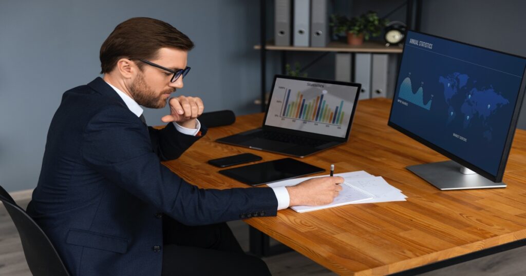 Empresario revisando gráficos en una laptop y con una libreta de notas