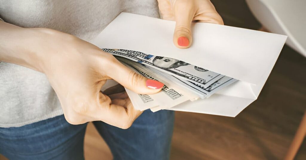 Mujer guardando dinero dentro de un sobre de color blanco