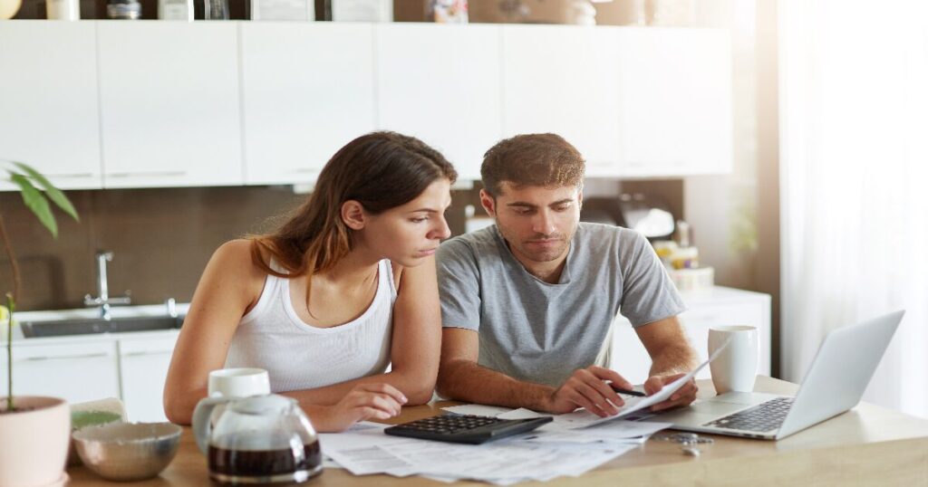 Familia sonriente revisando presupuesto doméstico en mesa de comedor
