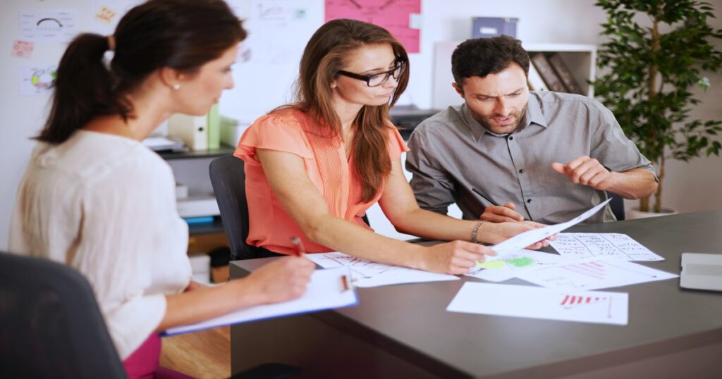  Equipo de trabajo reunido en una sala de juntas revisando informes
