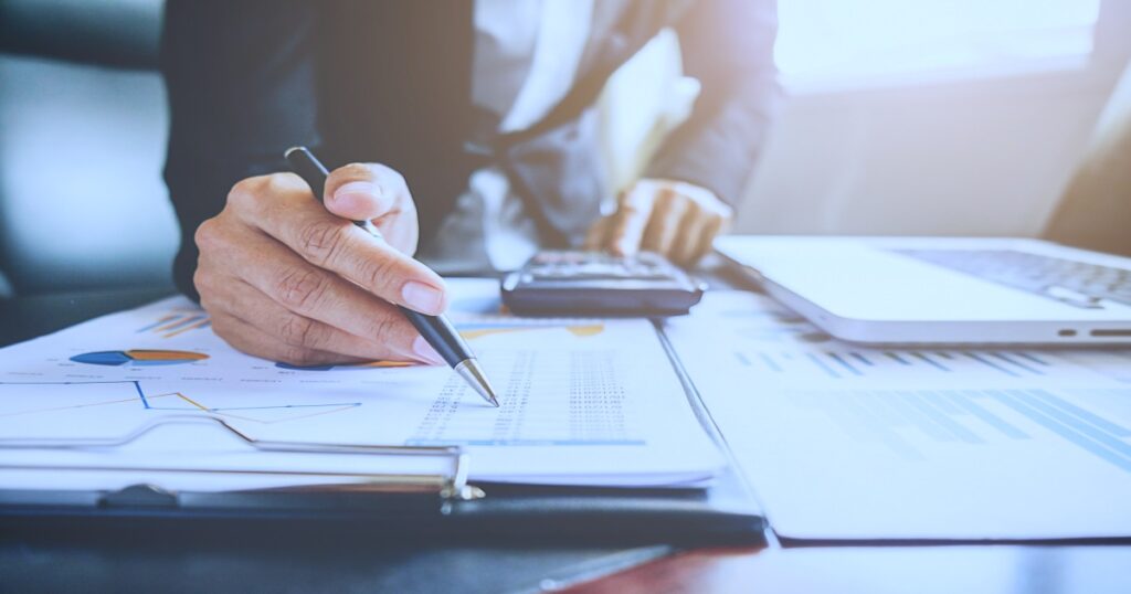 Hombre con traje analizando documentos, analizando documentos financieros, con laptop y calculadora