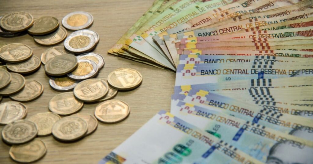 Billetes y monedas sobre mesa - Endeudamiento