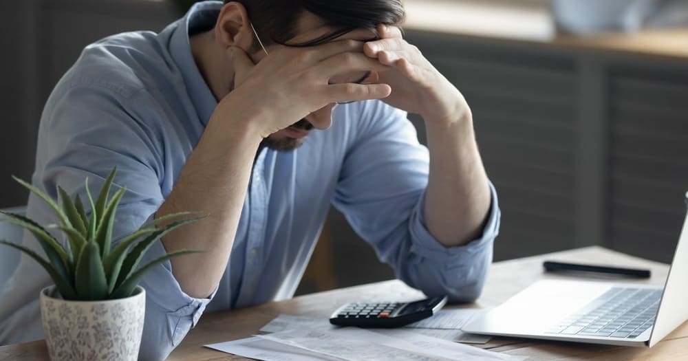 Persona preocupada revisando cuentas en mesa con calculadora