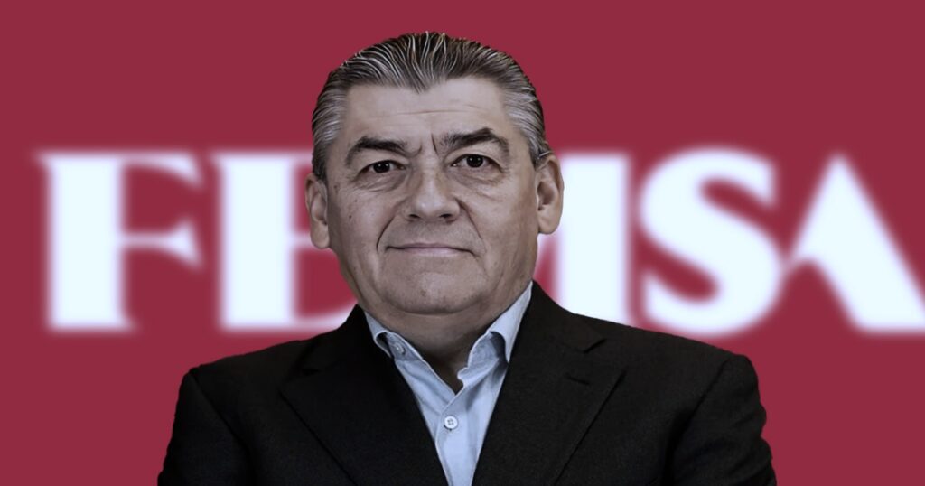 José Antonio Fernández Carbajal con traje oscuro y camisa clara, posando frente a un fondo rojo con el logotipo de FEMSA desenfocado.
