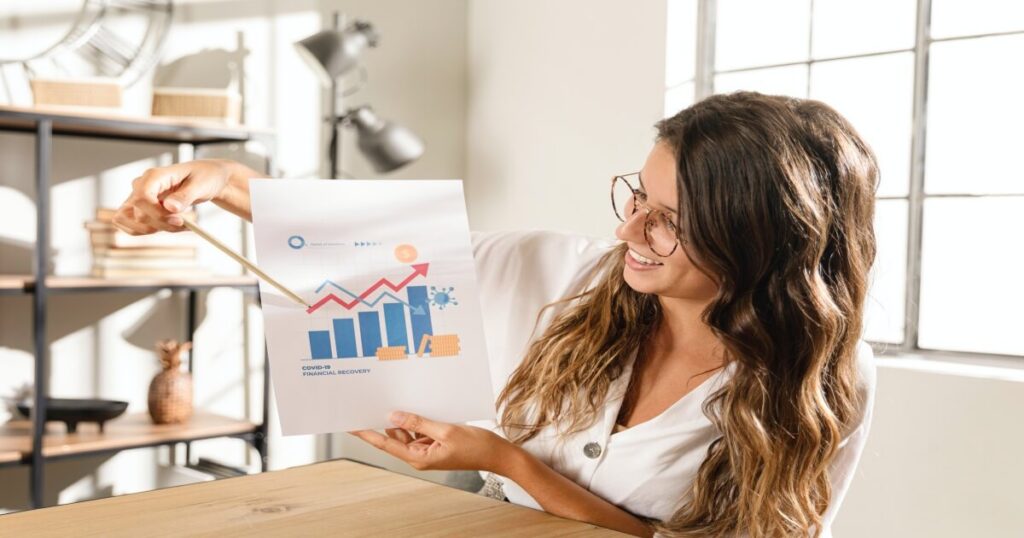 Mujer feliz sosteniendo y señalando una gráfica de crecimiento