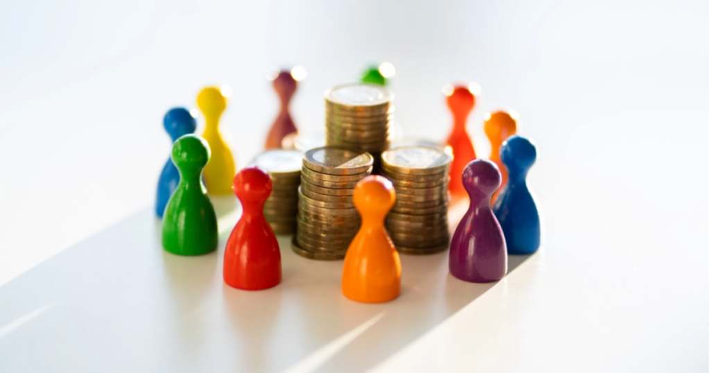 Fichas de colores alrededor de montones de monedas - Financiamiento colectivo o crowdfunding