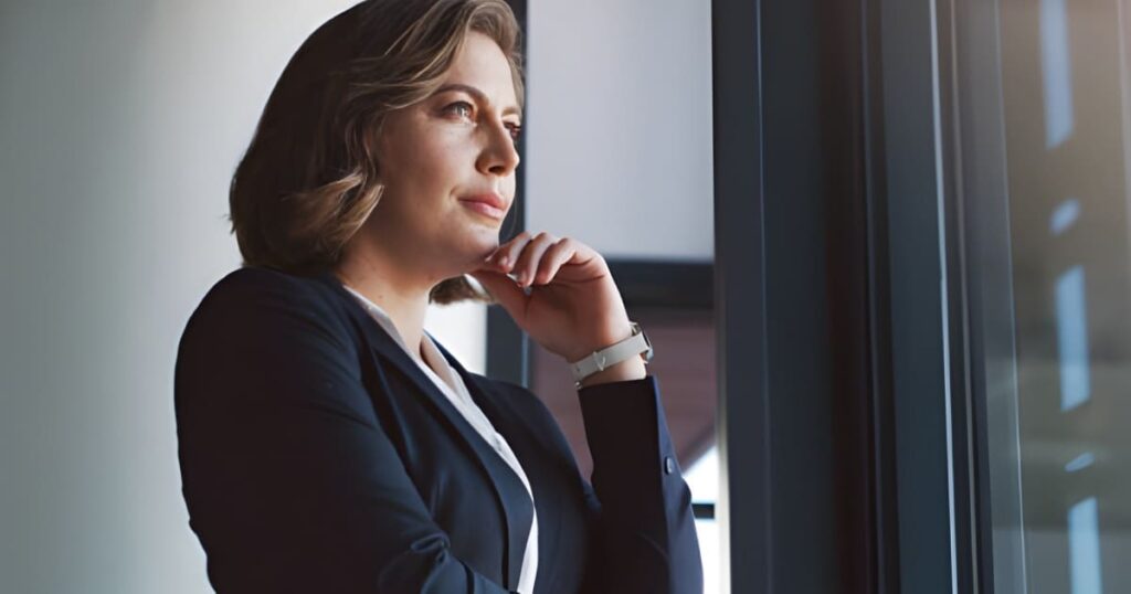 Mujer empresaria observando a través de una ventana - Visión y estrategia empresarial - Liderazgo estratégico