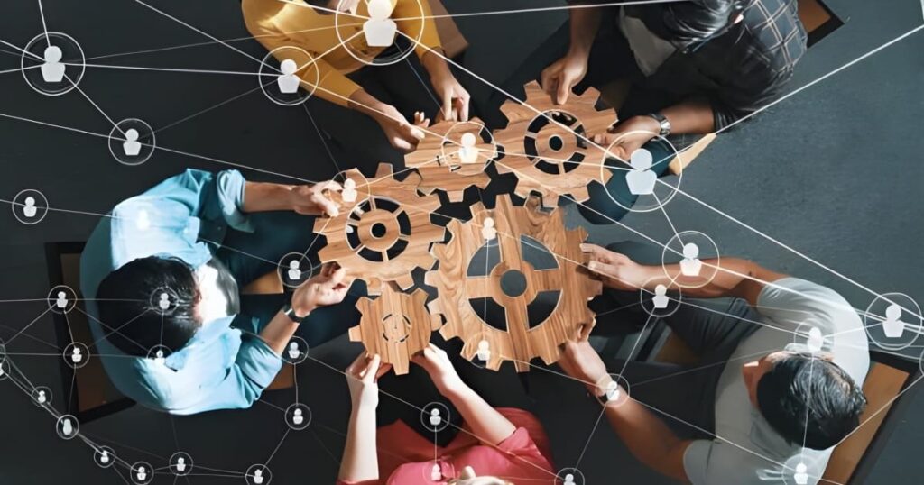 Toma cenital de grupo de personas uniendo figuras que representan engranajes de distintos tamaños