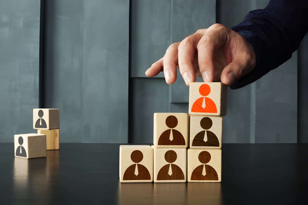 Mano de hombre apilando unos cubos de madera con representaciones de personas