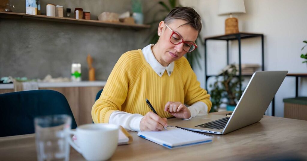 Mujer tomando notas frente a laptop