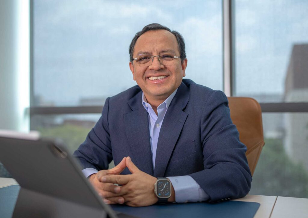 Ernesto Reséndiz López sentado en una oficina viendo sonriente hacia la cámara