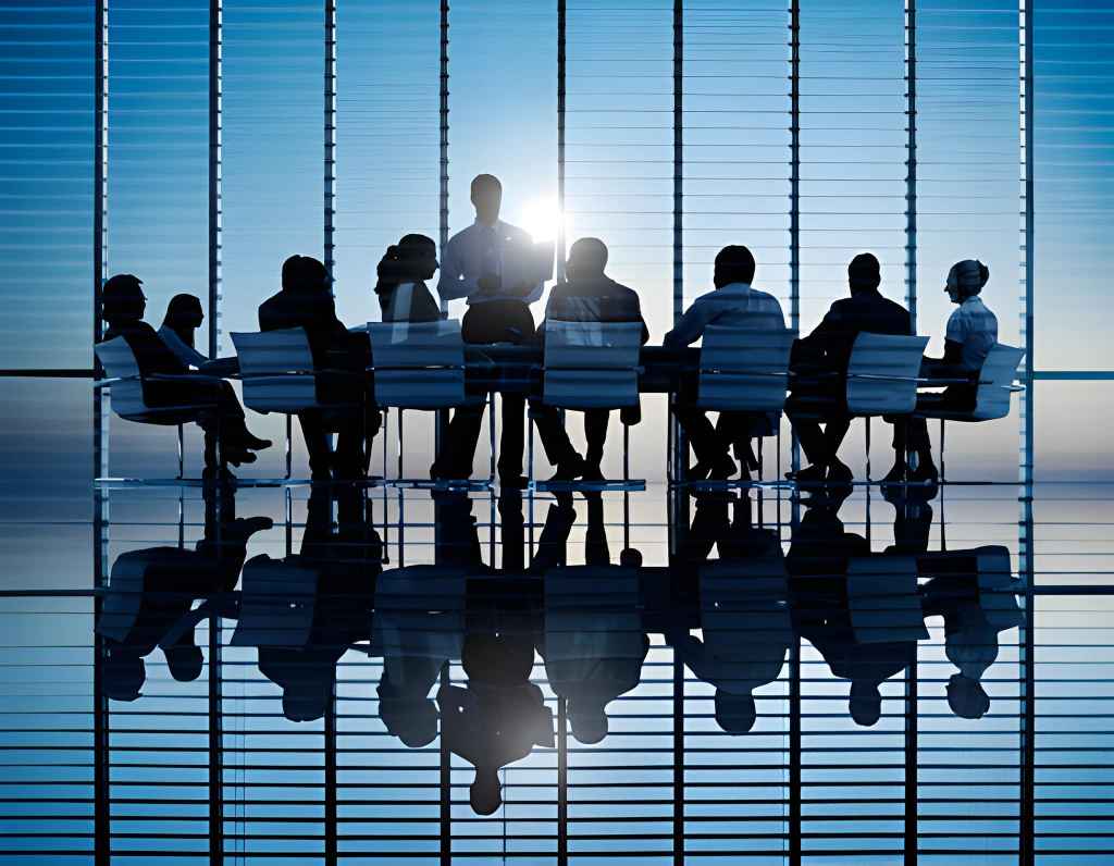  Hombre de pie con laptop frente a grupo de personas sentadas alrededor de mesa de trabajo
