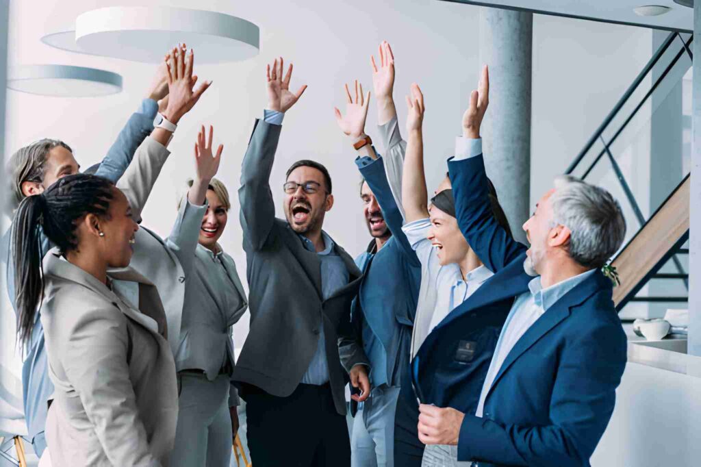  Personas de equipo de trabajo festejando con un grito y una de sus manos levantadas