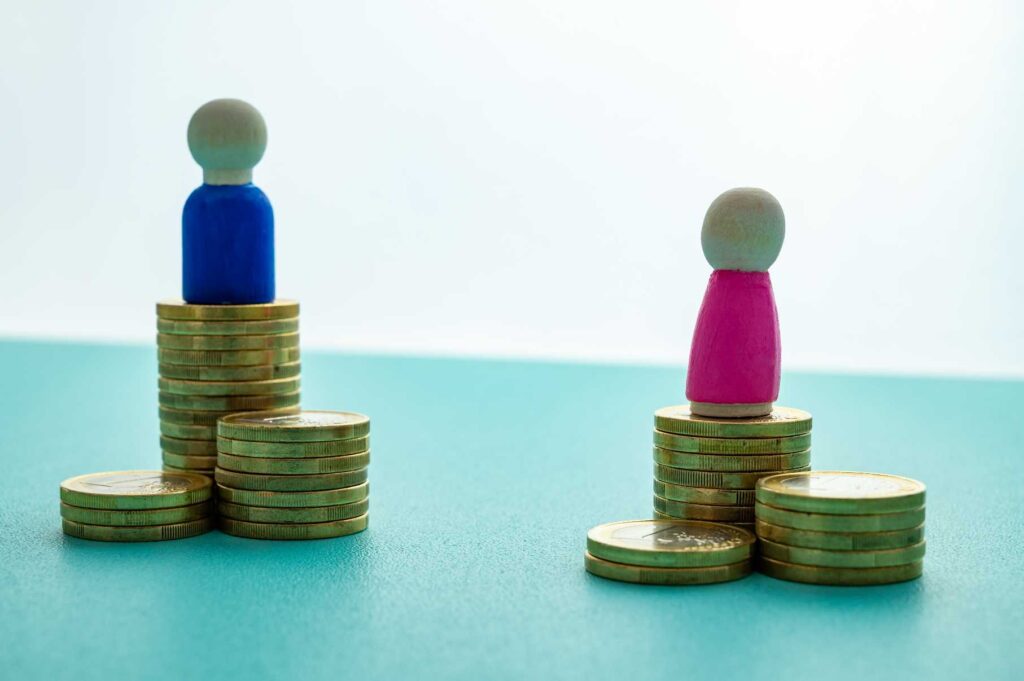 Figura femenina y masculina sobre pilas de monedas desiguales frente a gráficas de crecimiento distintas 
