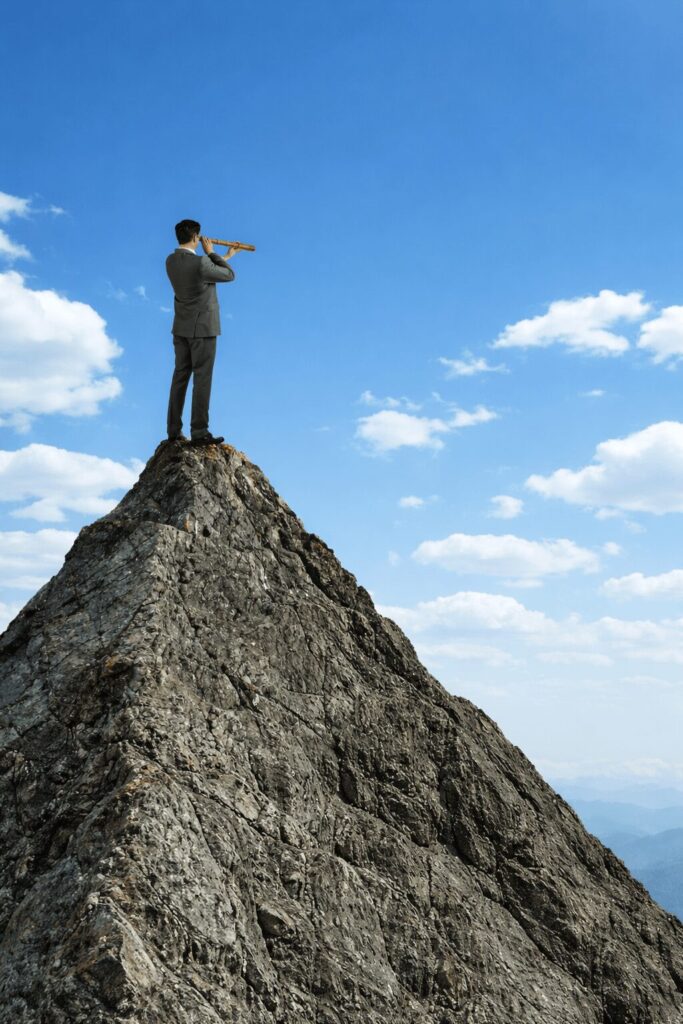 Hombre con catalejo sobre acantilado viendo el cielo con nubes