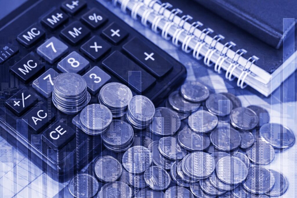 Monedas sobre y junto a una calculadora y libretas
