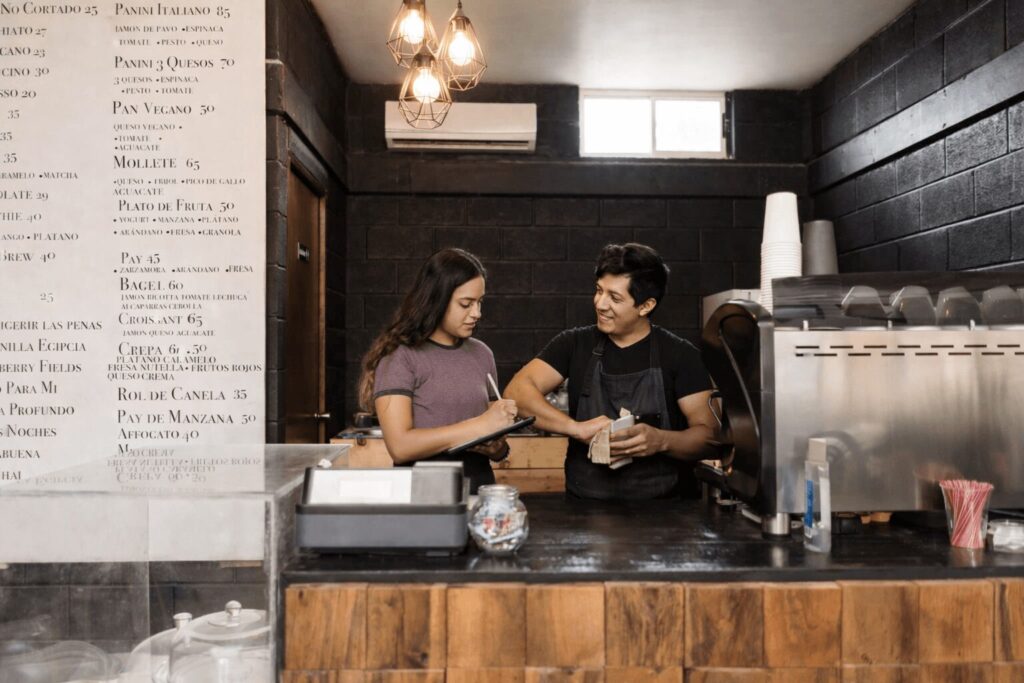 Mujer y hombre jóvenes tras mostrador de cafetería
