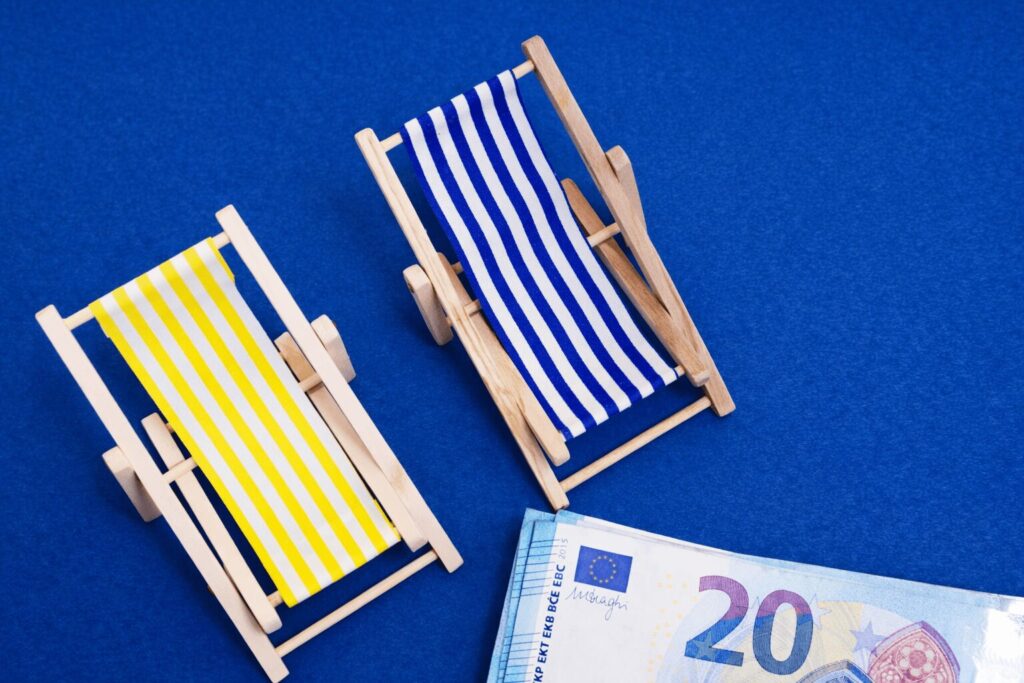 Sillas de playa miniatura junto a billetes sobre fondo azul